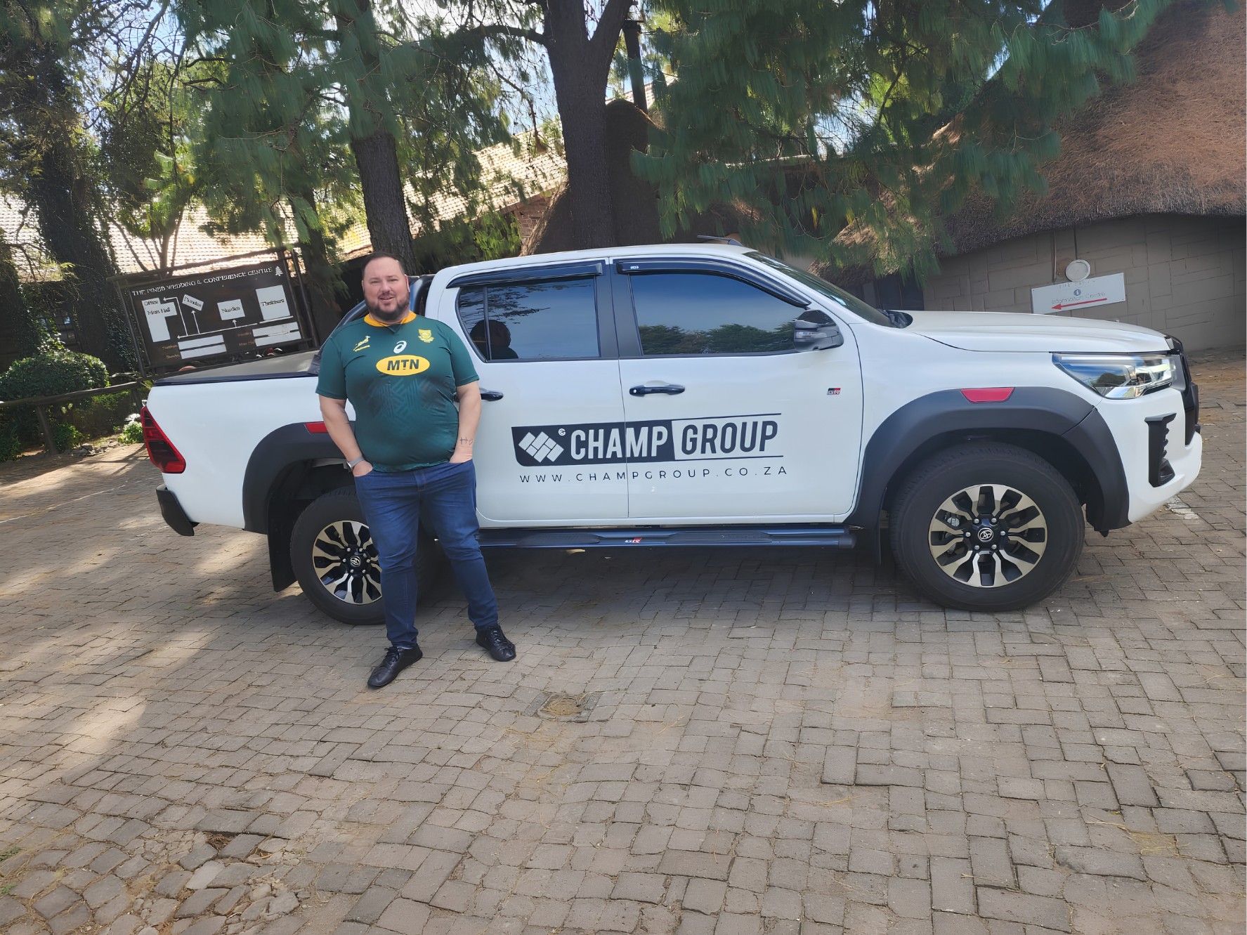 Johan Pieters in a Springbok jersey beside a white Champ Group bakkie at The Pines